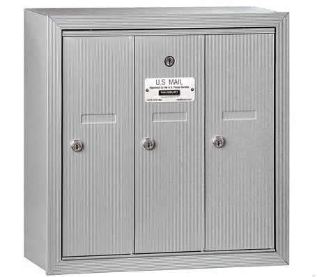 Silver three-door wall-mounted mailbox with locks and U.S. Mail label.