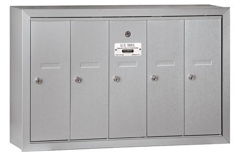 Wall-mounted silver multi-unit mailbox with five compartments and a U.S. Mail label.