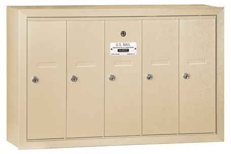 Beige wall-mounted mailbox unit with five locked compartments and a U.S. Mail label.