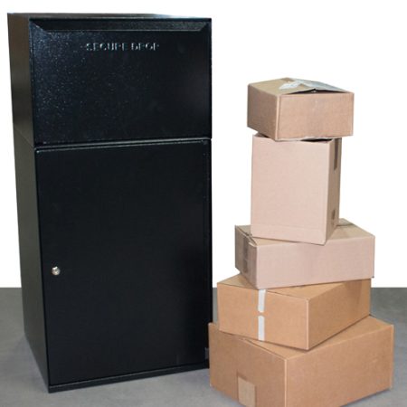 Black secure drop box next to a stack of cardboard packages on a gray surface.