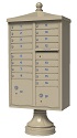 Beige pedestal-mounted cluster mailbox with multiple compartments and decorative top.