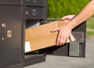 Hands loading a box into a parcel locker.